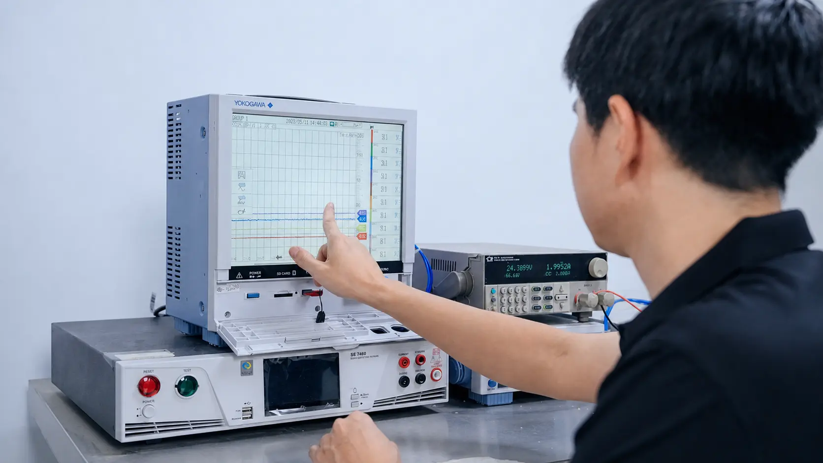 Laboratory technician reviewing electrical test results on precision measurement equipment
