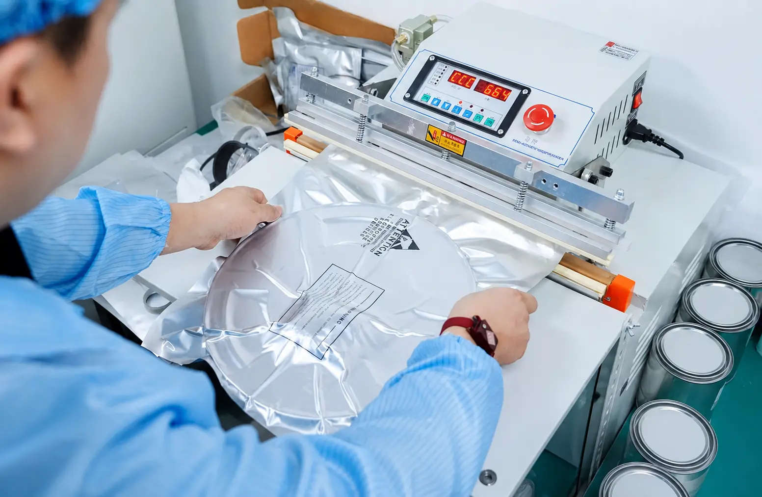 Clean-room technician visually inspecting and sealing a packaged electronic component reel